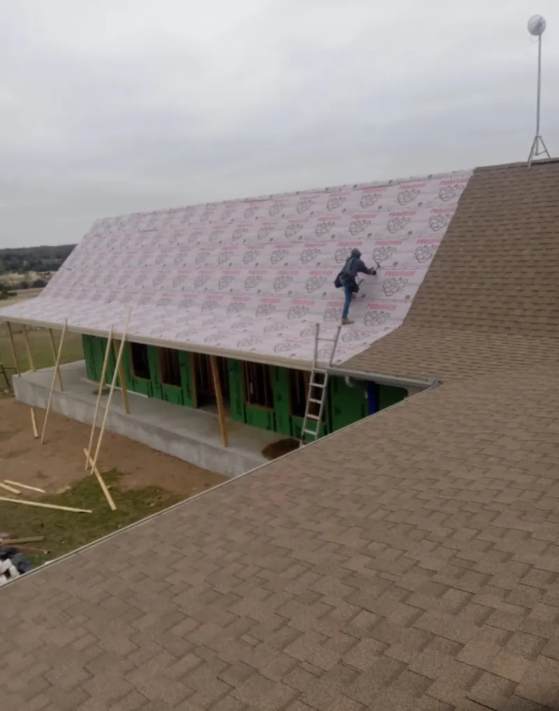 Worker preparing underlayment for a metal roof installation in Fairview